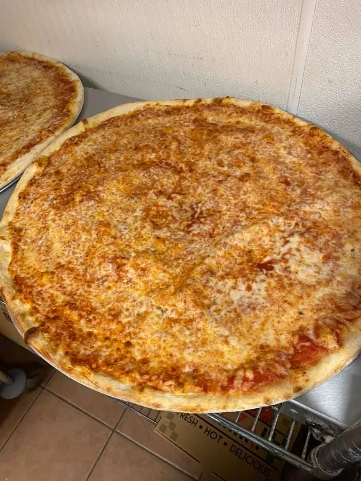 Whole cheese pizza fresh from the oven on a pizza pan